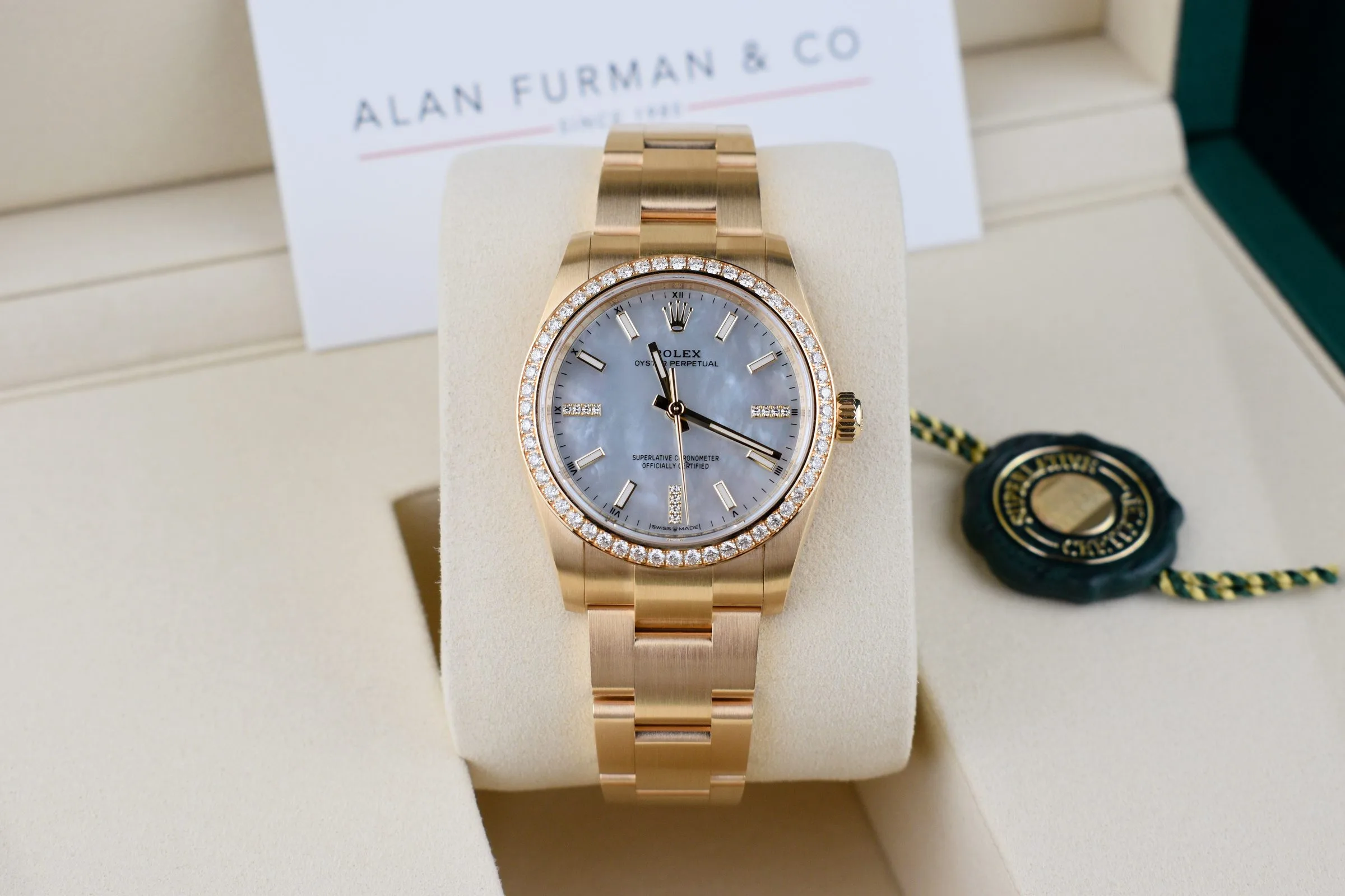 Rolex Oyster Perpetual 34 in yellow gold with a diamond-set bezel and a white mother-of-pearl dial, presented in its box with an Alan Furman & Co card